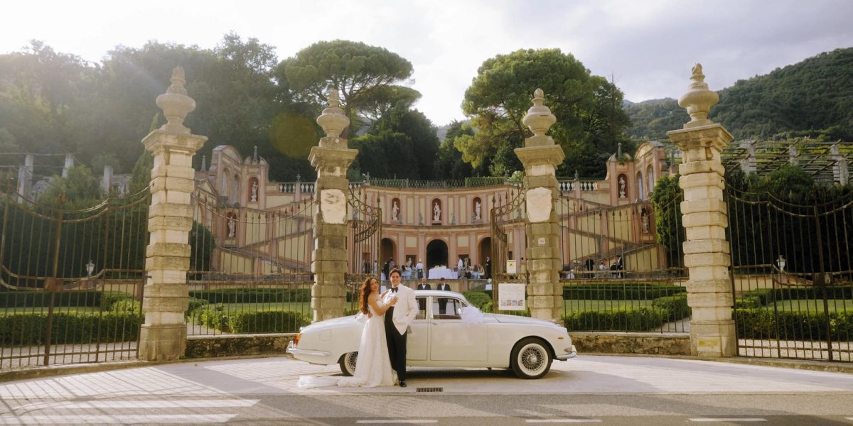 Vintage wedding car at the ornate stone gates of Villa Bettoni on Lake Garda, Italy