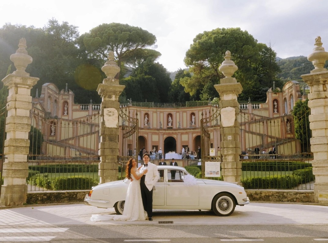 Vintage wedding car at the ornate stone gates of Villa Bettoni on Lake Garda, Italy