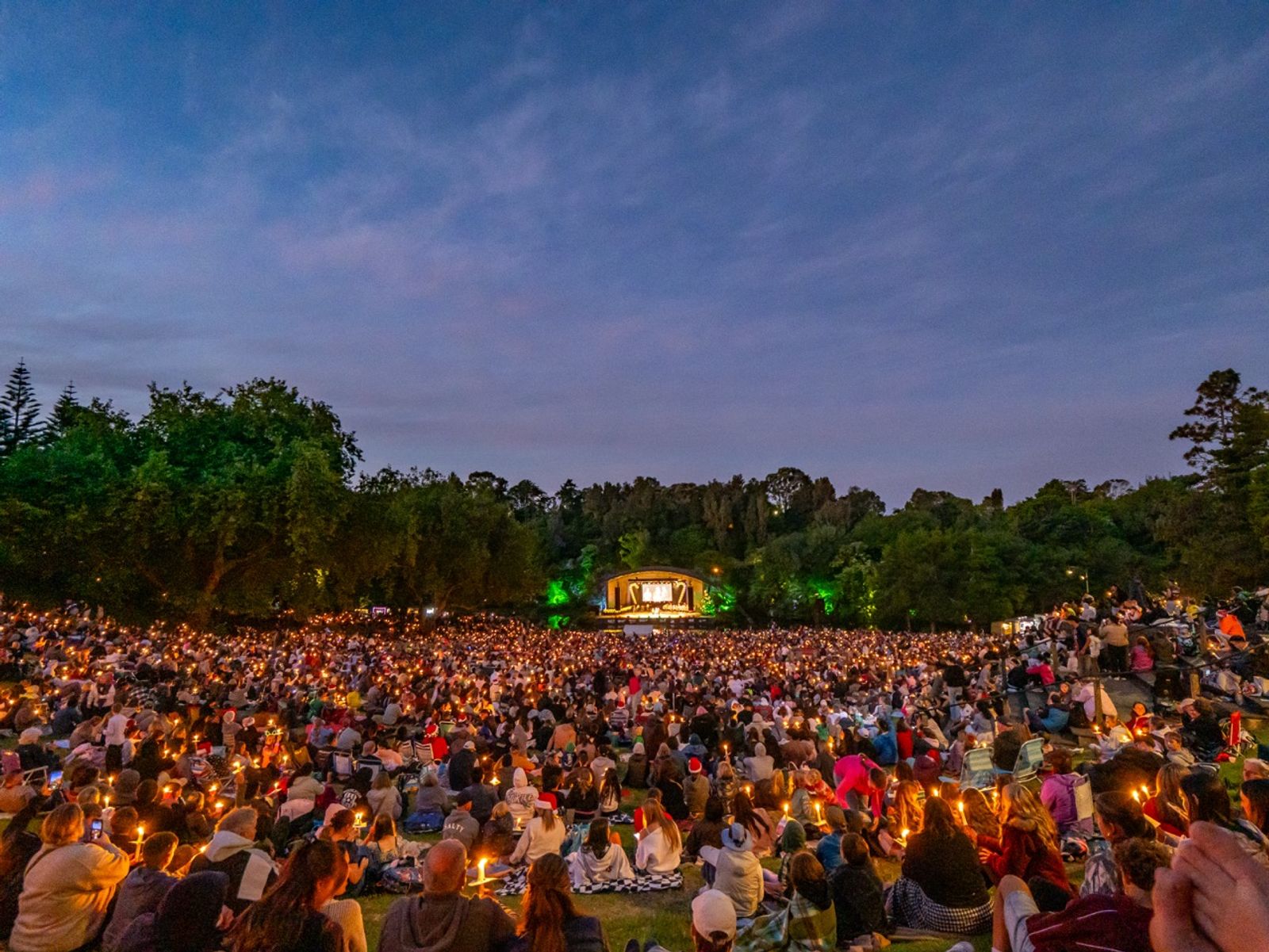 The Bowl of Brooklands amphitheatre at dusk, the stage glowing across the lake