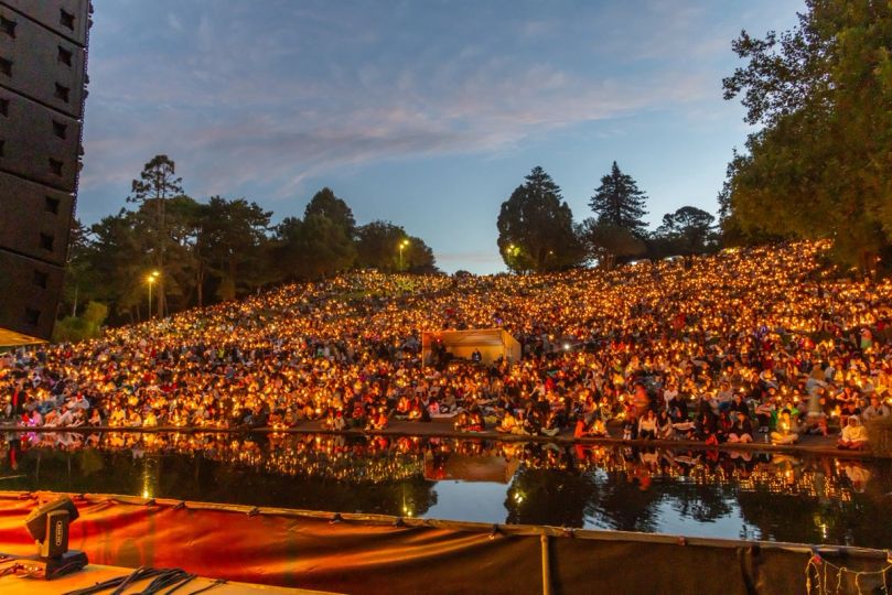Crowd with candles reflected in the lake