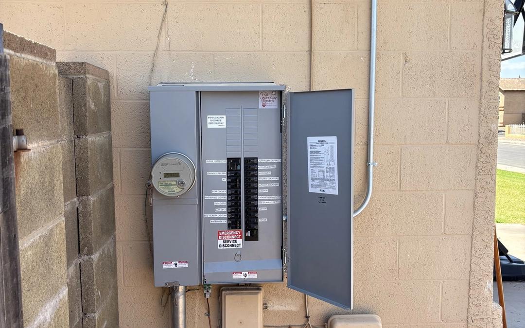 New meter and breaker panel combo mounted on a tan block wall with fresh conduit