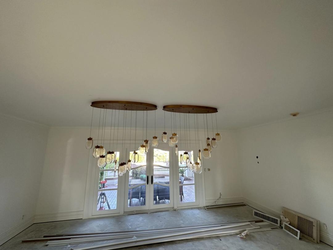 Cluster of glass pendant lights on two round wood canopies in an empty room under renovation