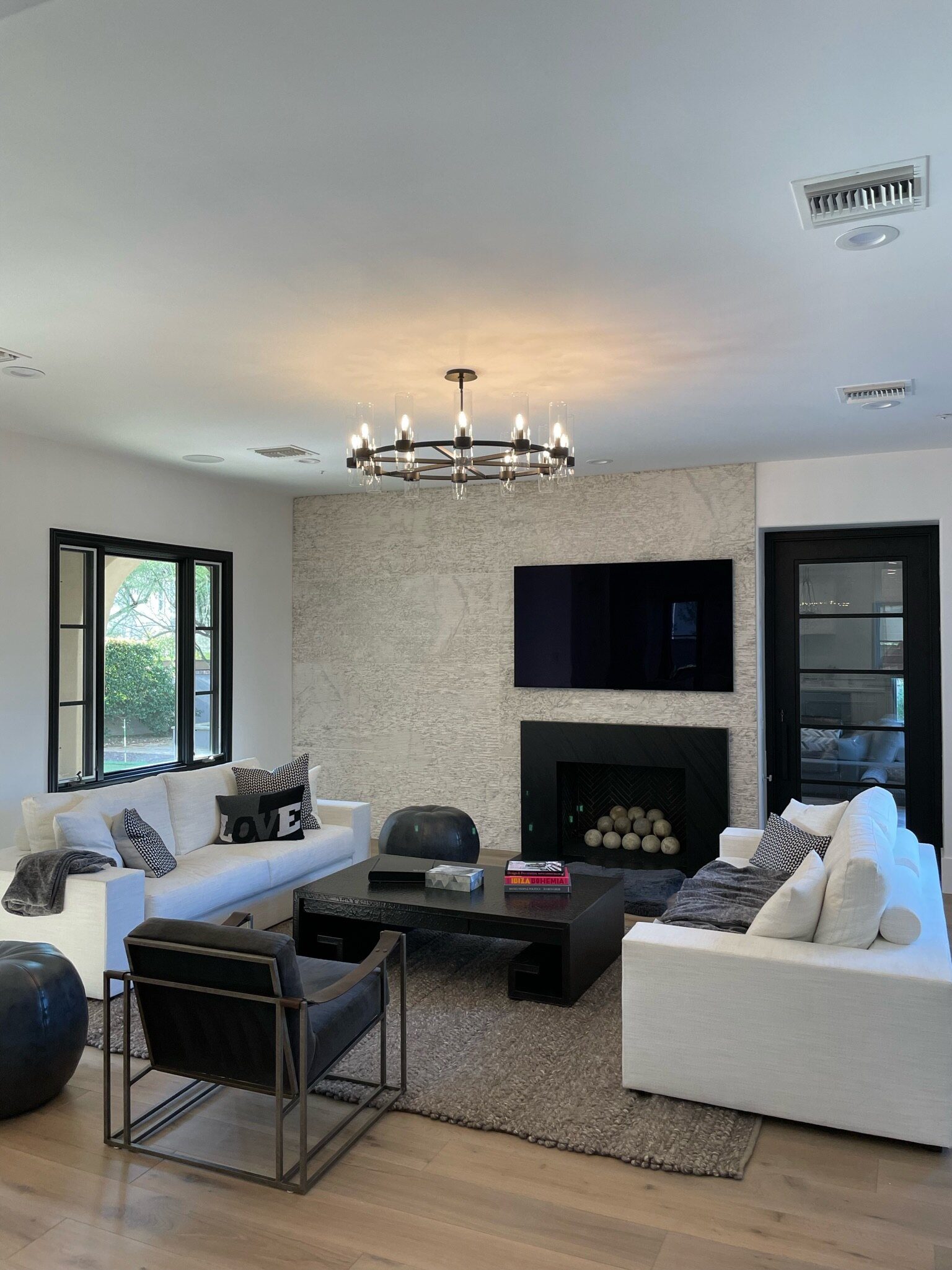 Bright living room with a round candle-style chandelier over white sofas and a fireplace
