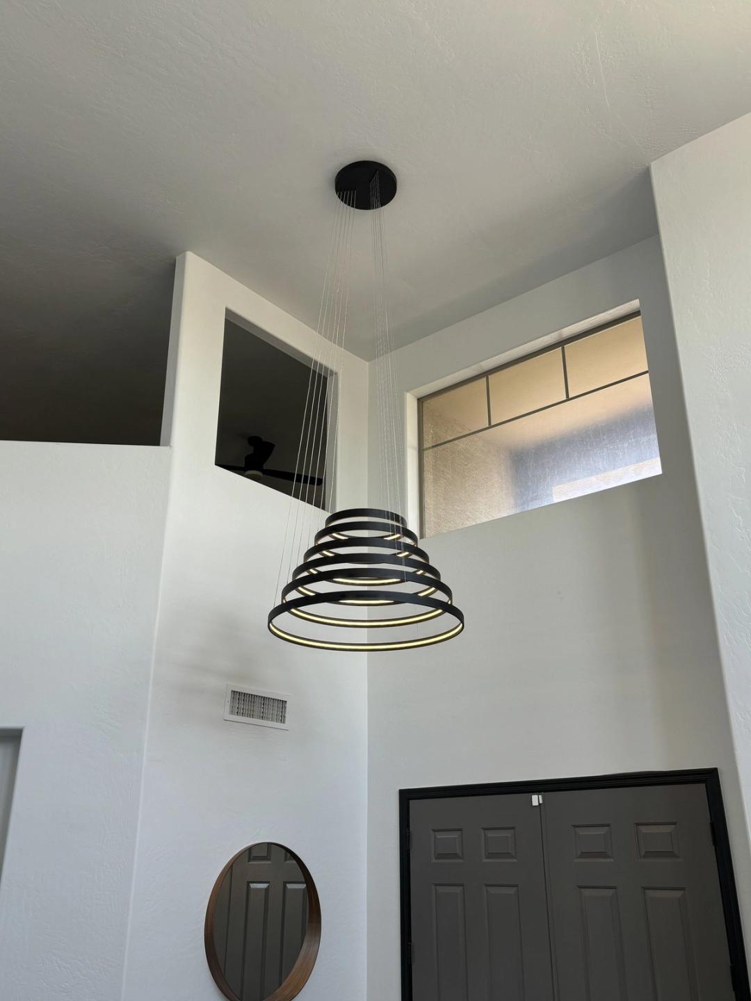 Spiral ring LED pendant hanging in a two-story entry with clerestory windows