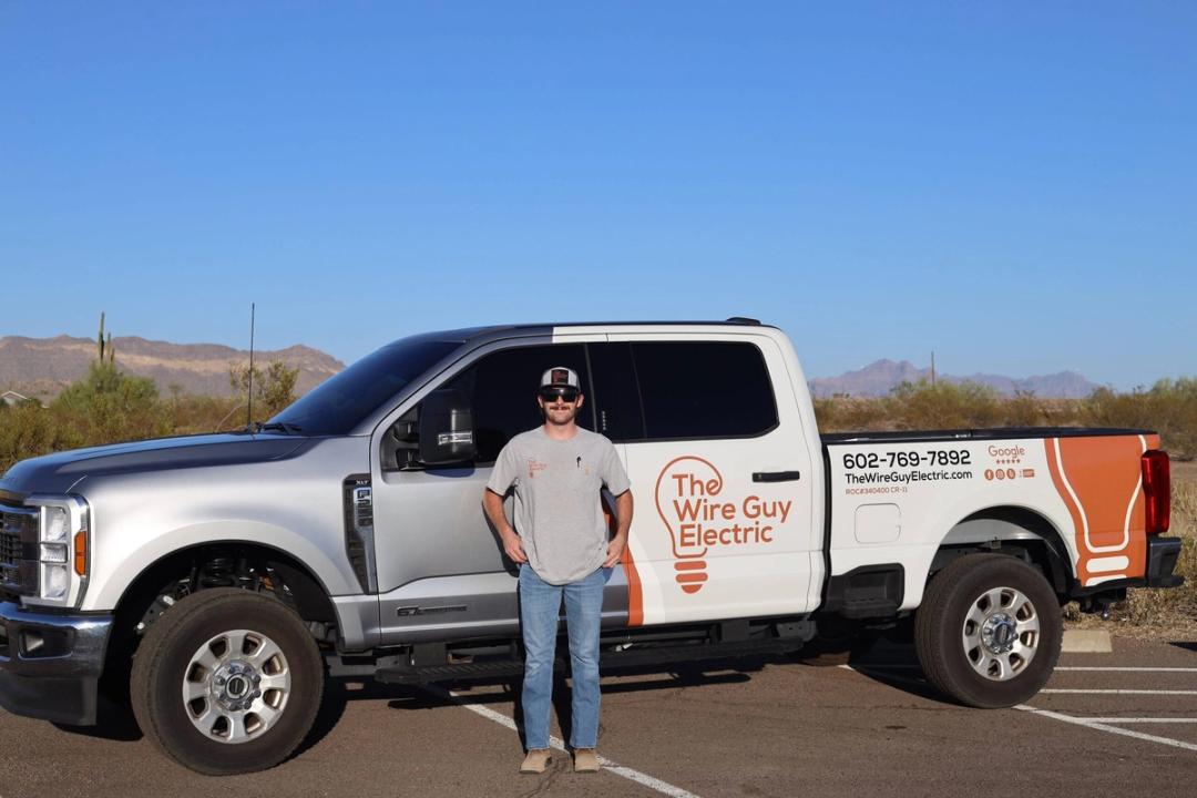 Electrician standing in front of a branded Wire Guy Electric pickup in the desert