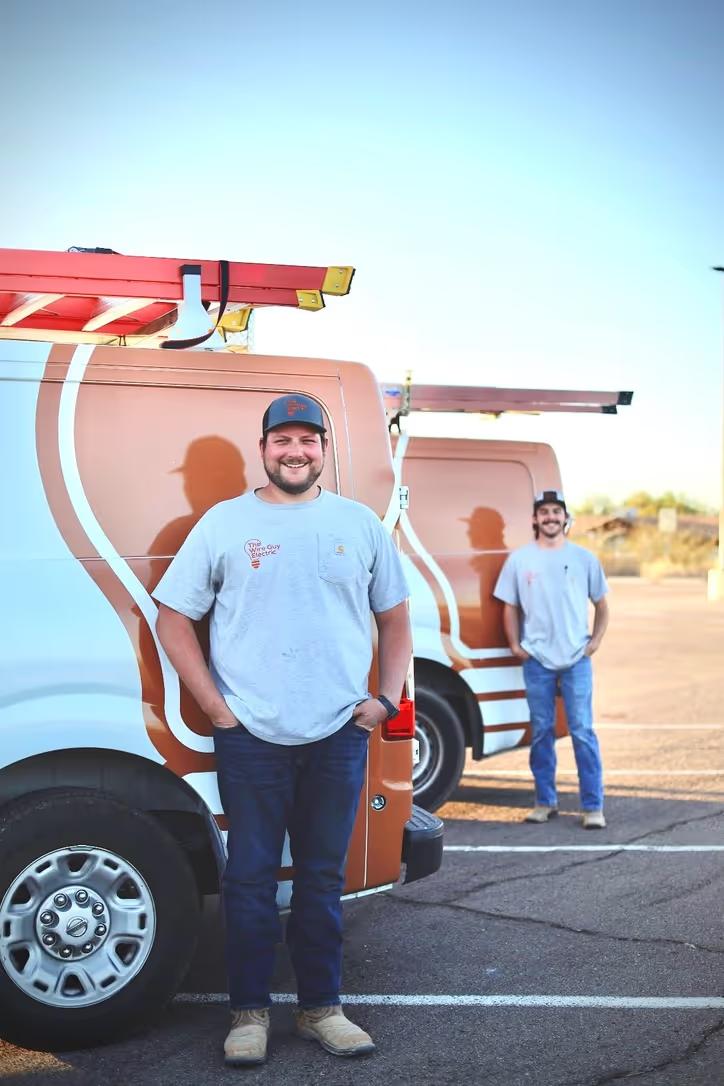 Owner Steven Taylor standing beside a Wire Guy Electric service van with a ladder rack, a second technician behind him