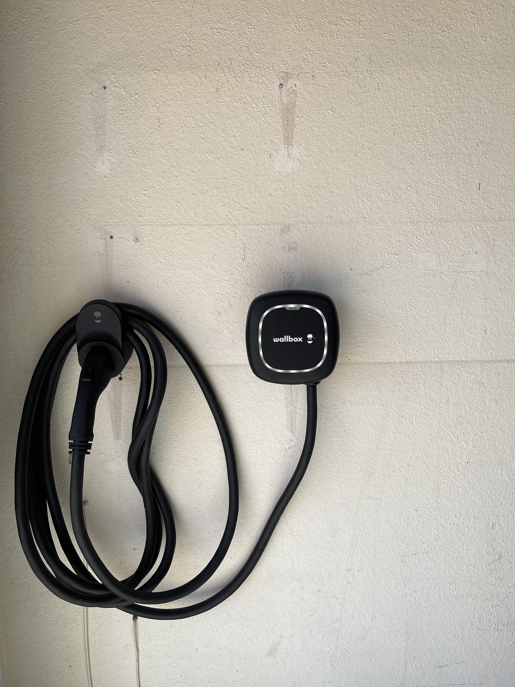 Wallbox EV charger with coiled cable mounted on a painted wall