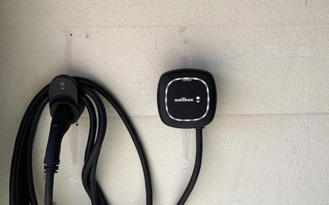 Wallbox EV charger with coiled cable mounted on a painted wall