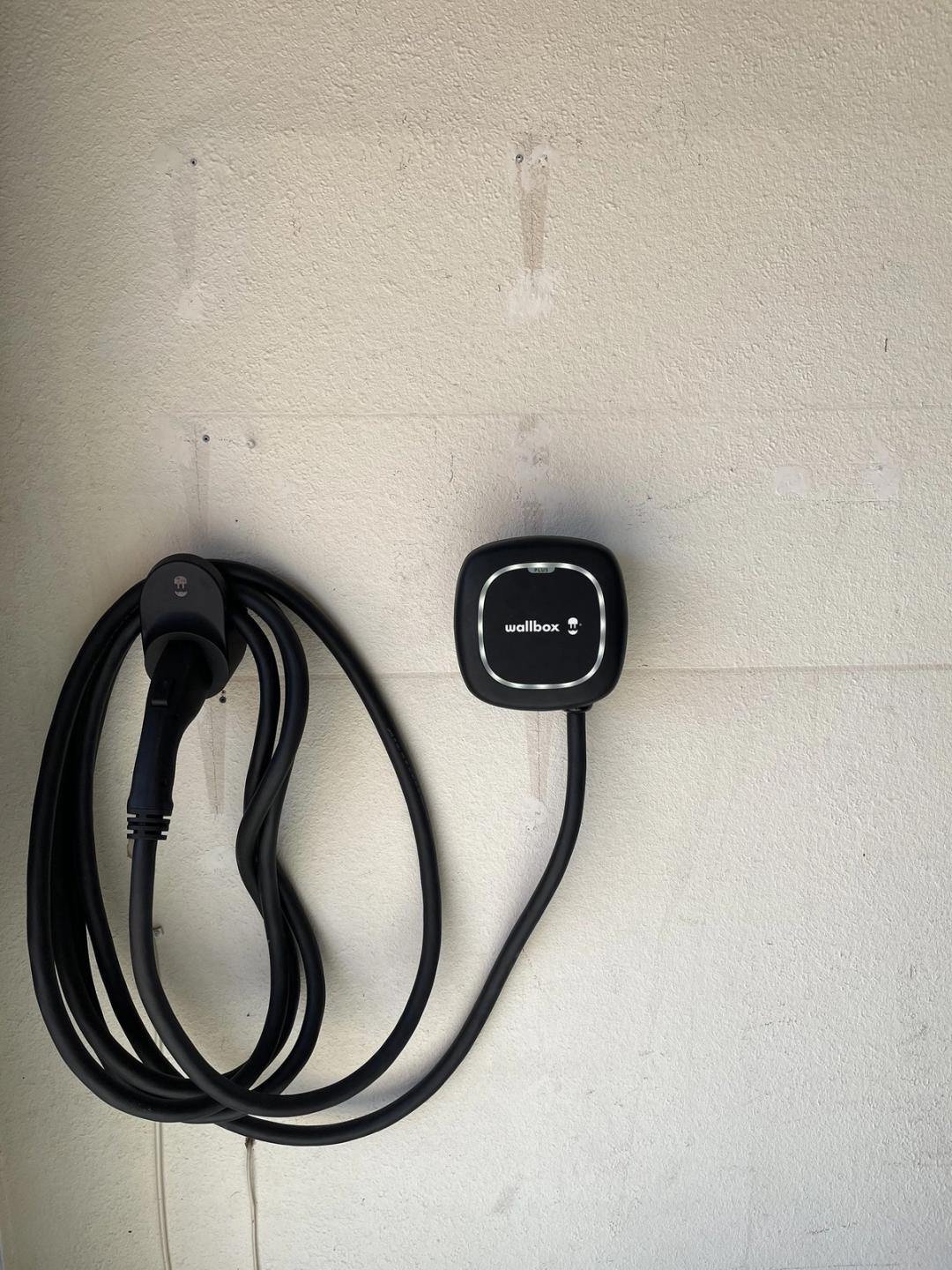 Wallbox EV charger with coiled cable mounted on a painted wall