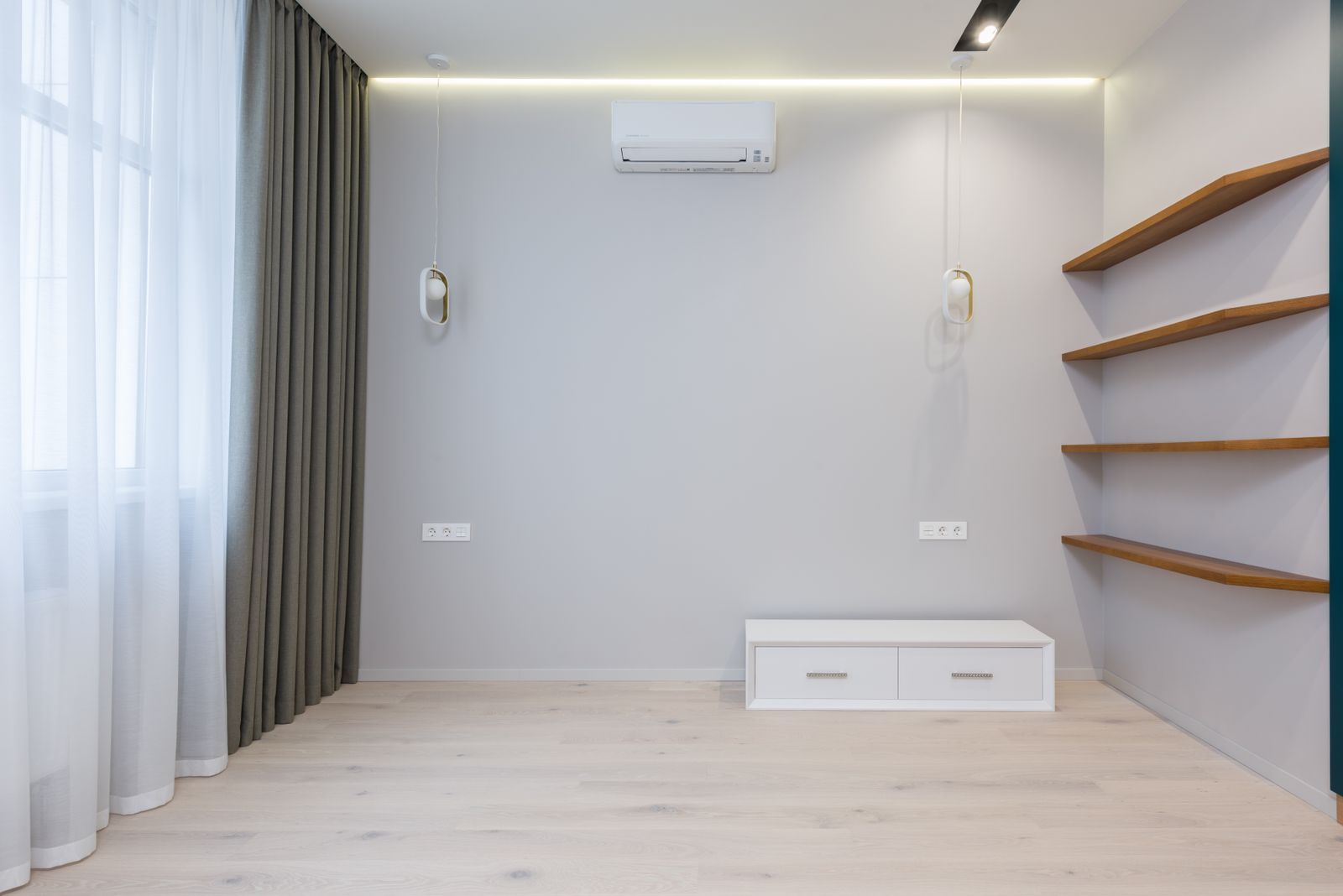 A wall-mounted ductless mini-split above an empty room with wood shelves and pendant lights