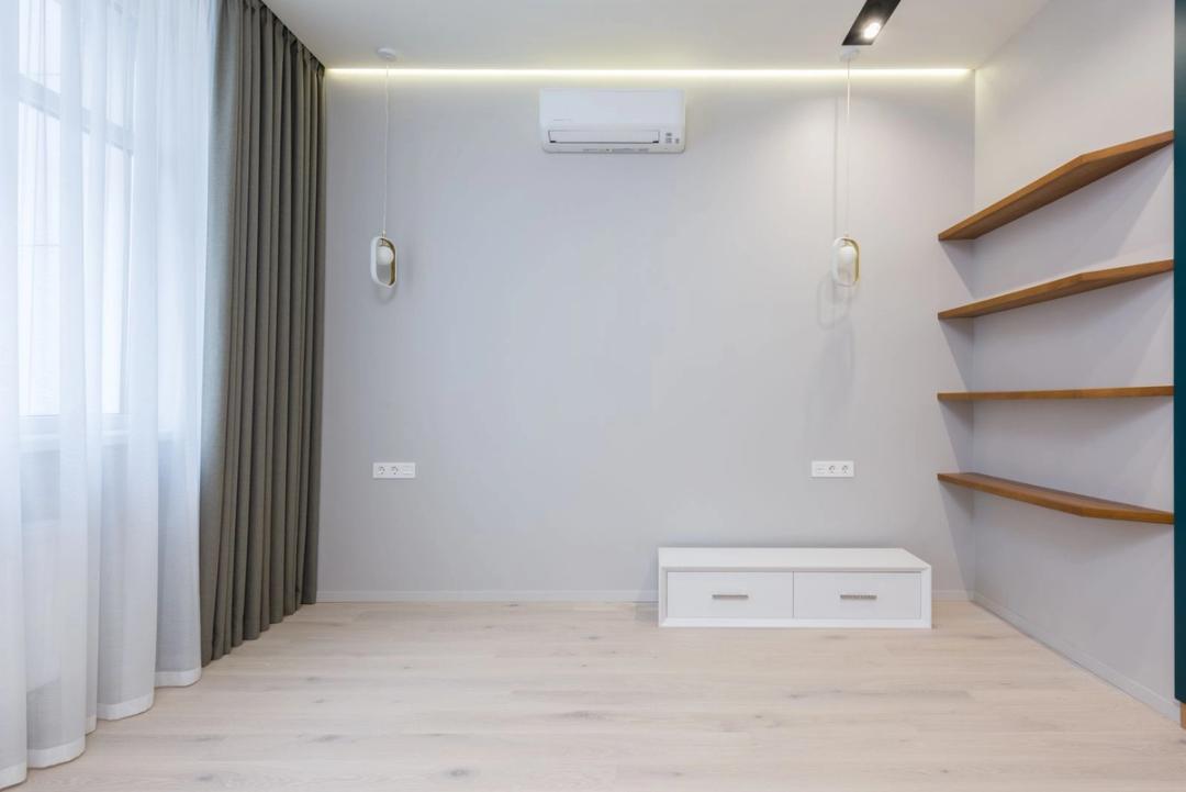 A wall-mounted ductless mini-split above an empty room with wood shelves and pendant lights
