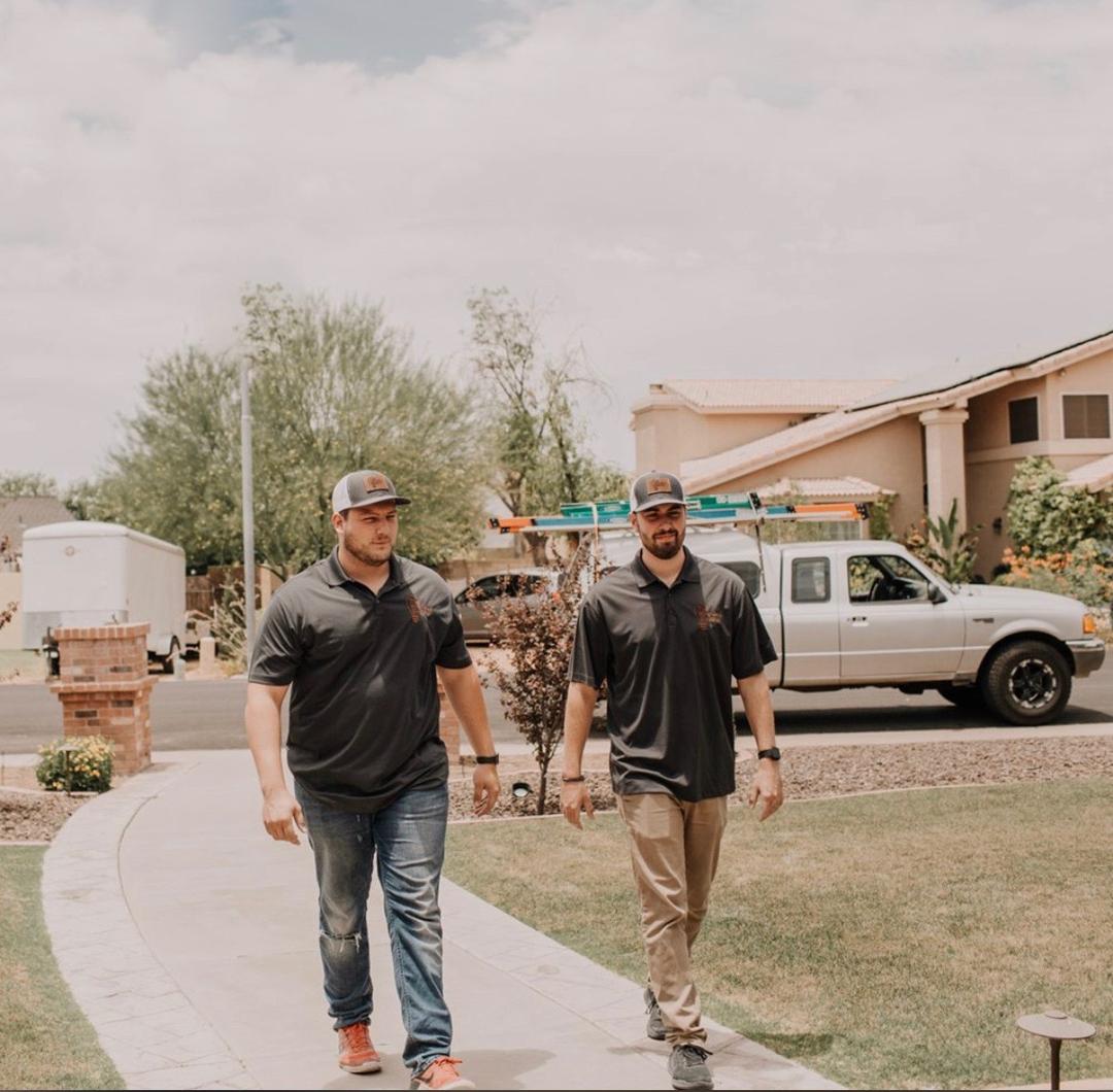 Two Wire Guy Electric technicians walking up a customer's front path in an Arizona neighborhood