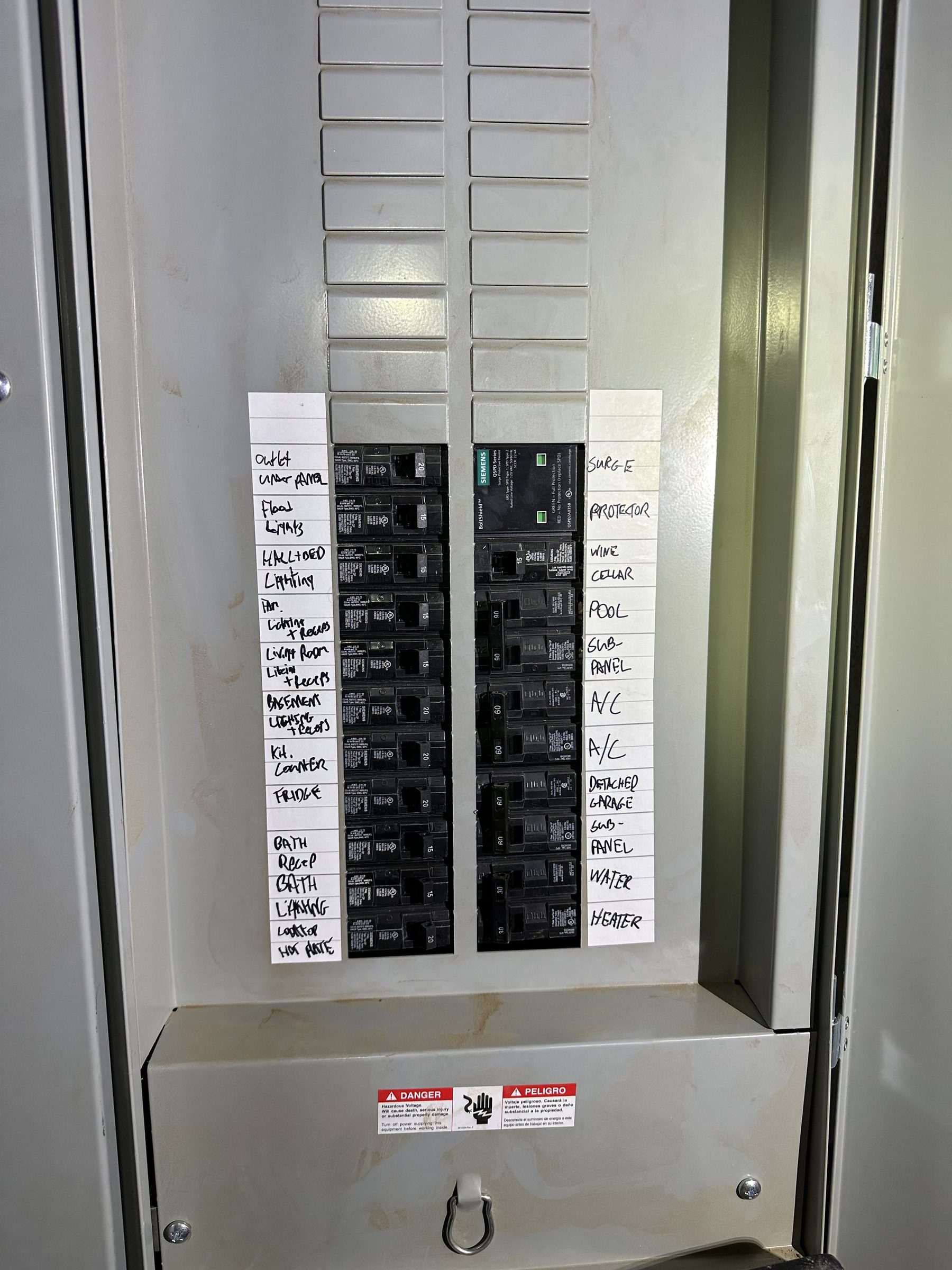 Panel with handwritten circuit labels including surge protector, pool and A/C breakers