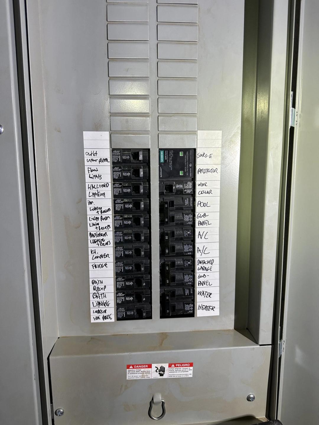 Panel with handwritten circuit labels including surge protector, pool and A/C breakers