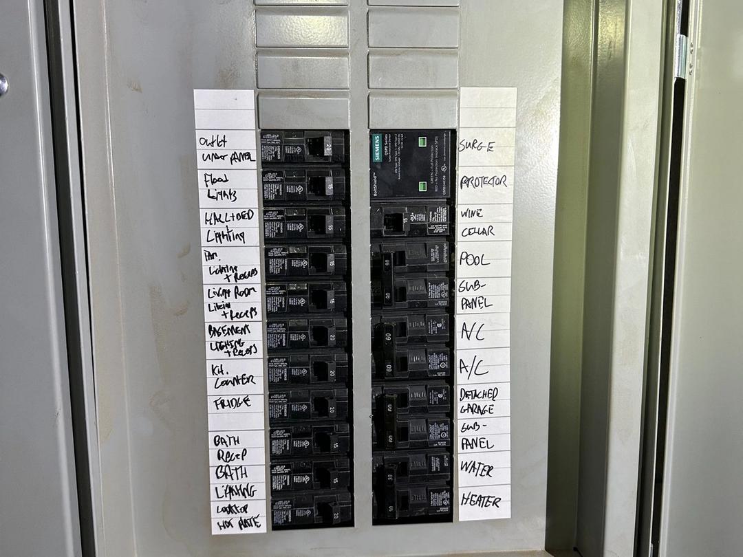 Panel with handwritten circuit labels including surge protector, pool and A/C breakers
