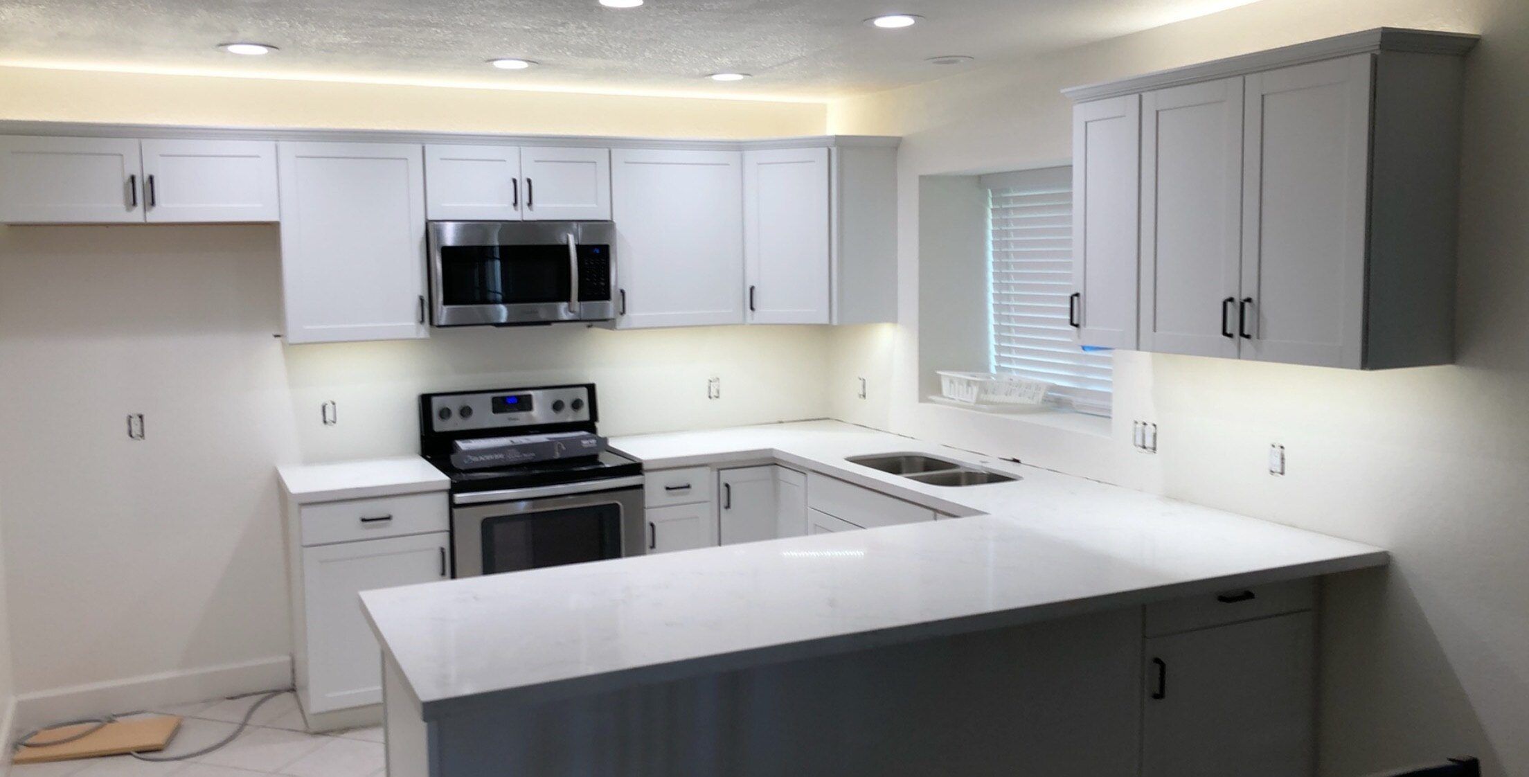 Bright white kitchen with under-cabinet LED lighting and recessed lights