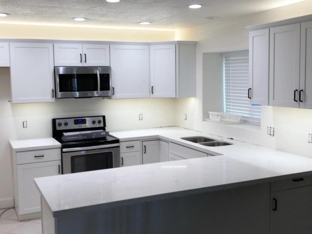 Bright white kitchen with under-cabinet LED lighting and recessed lights
