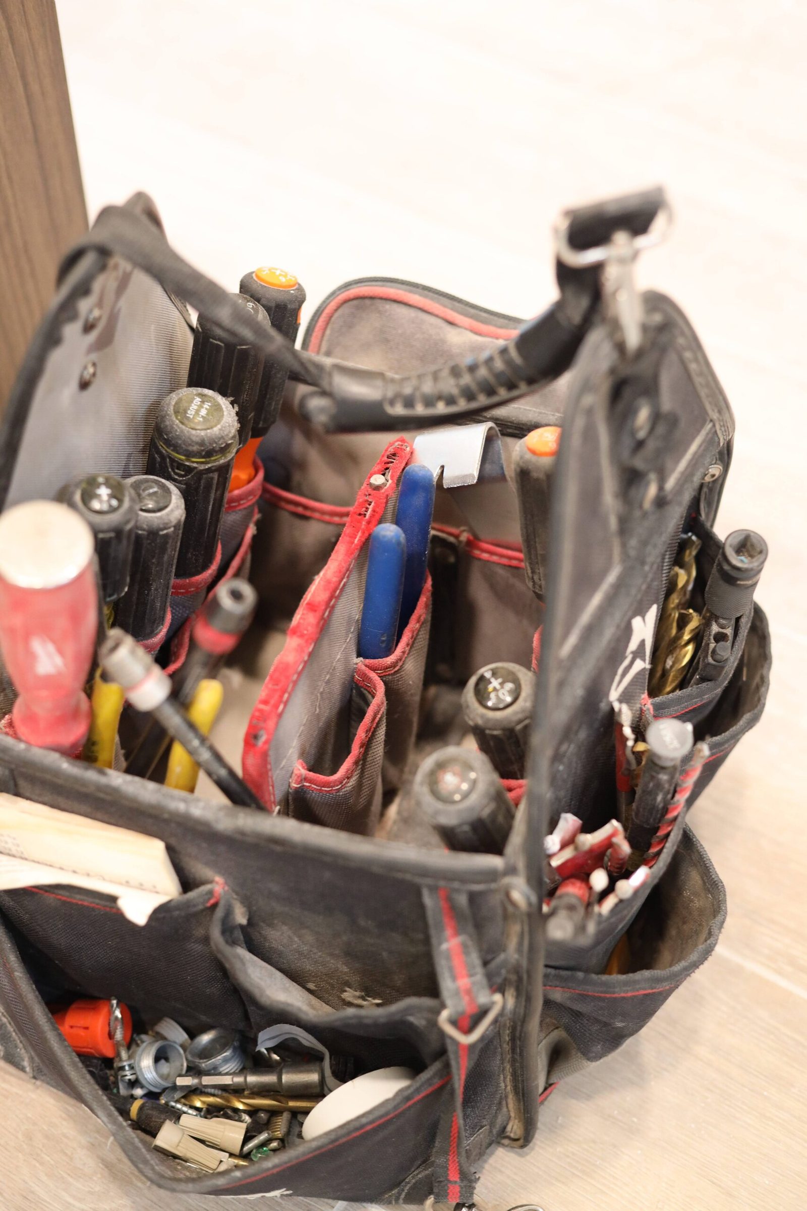 Open electrician tool bag filled with screwdrivers and pliers