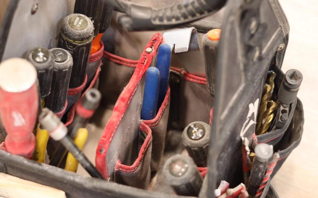Open electrician tool bag filled with screwdrivers and pliers