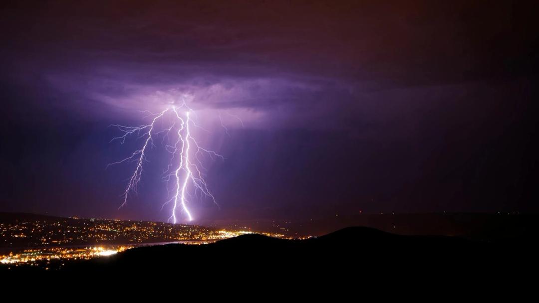 Lightning striking over the lights of a city at night