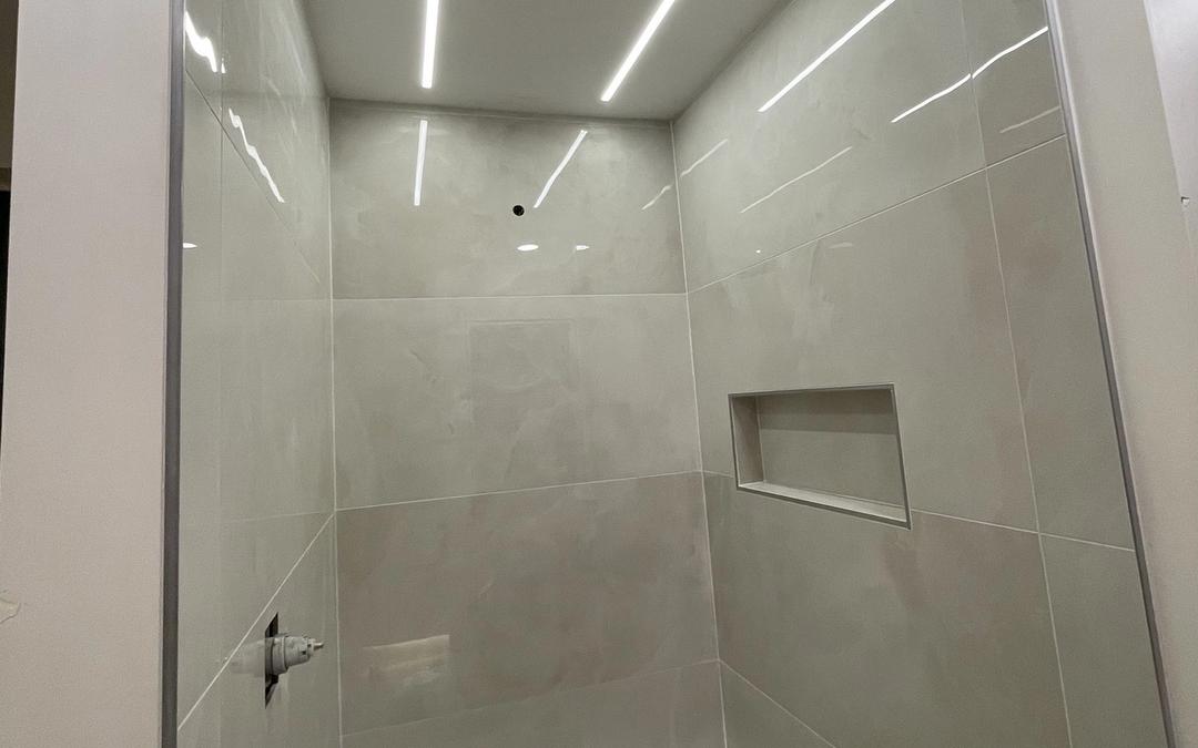 Modern tiled shower with linear LED lights recessed in the ceiling