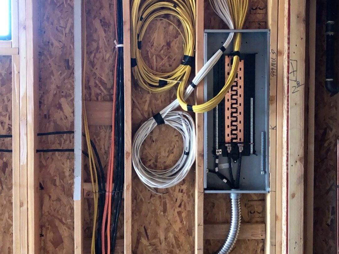 Open wall framing with coiled wire and a new subpanel during rough-in