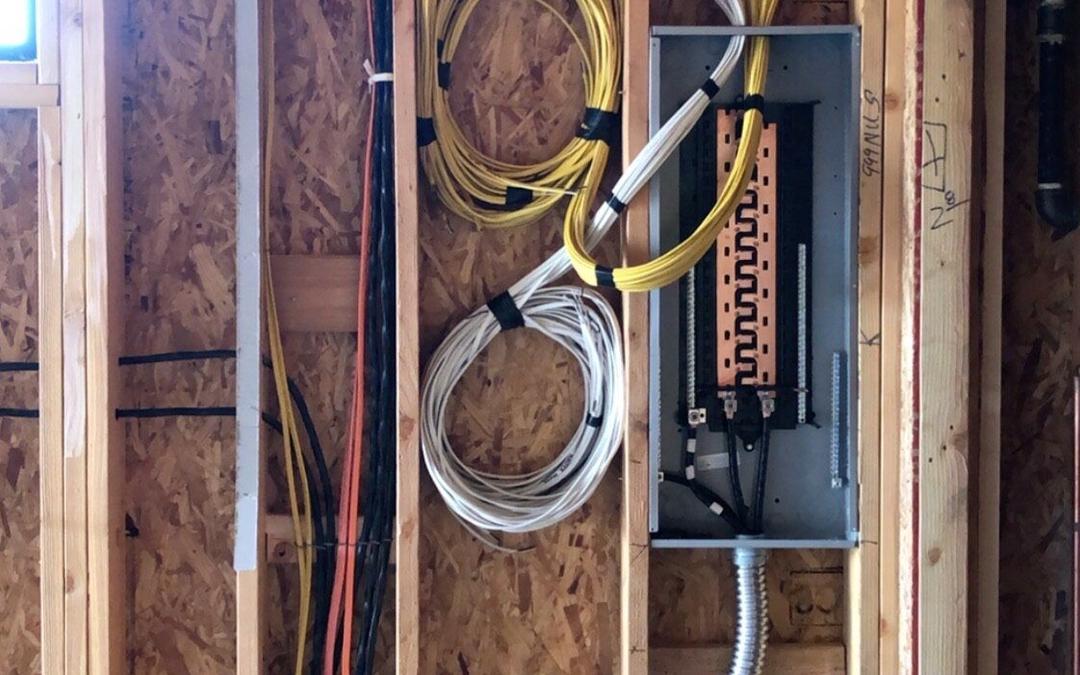 Open wall framing with coiled wire and a new subpanel during rough-in
