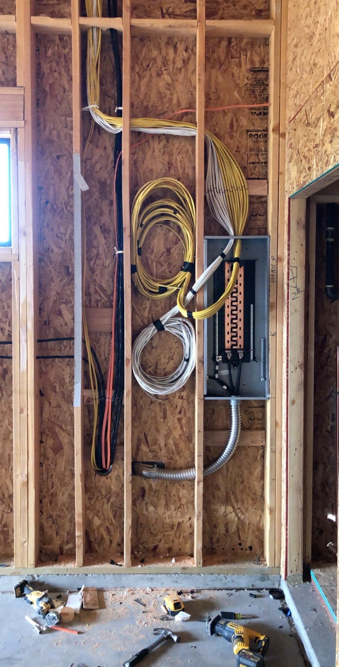 Open wall framing with coiled wire and a new subpanel during rough-in