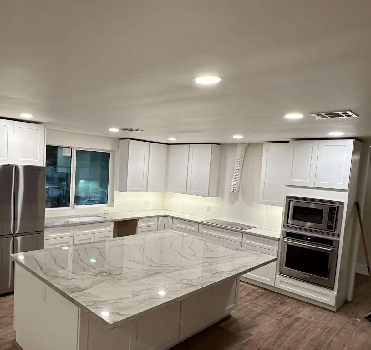 A remodeled kitchen at night lit by recessed ceiling lights
