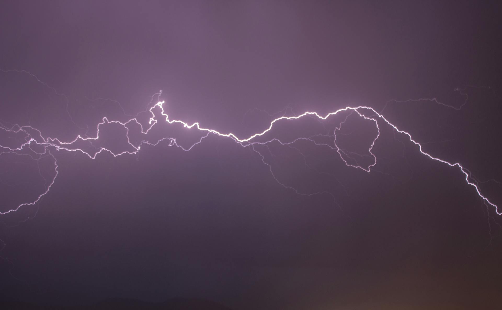 A long bolt of lightning branching across a purple night sky
