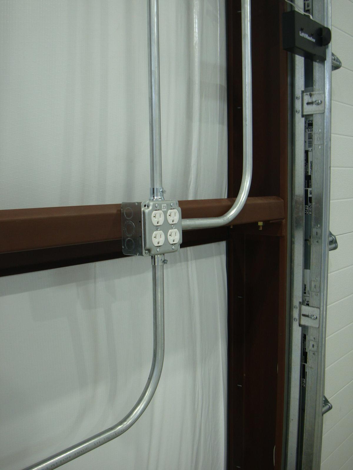 Surface-mounted conduit and duplex receptacle on a metal building wall