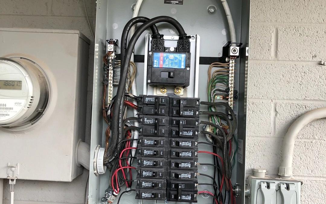 Neatly wired new Eaton breaker panel with the cover off next to a meter