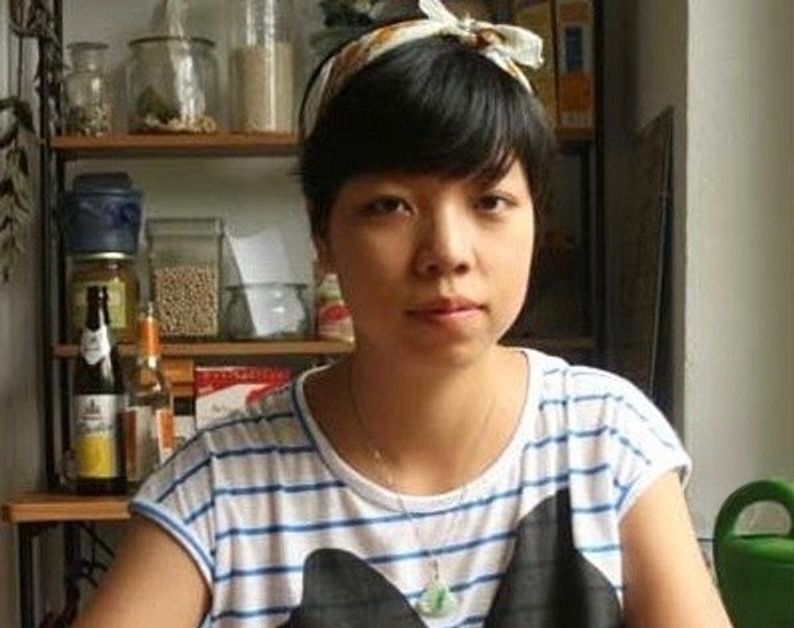 Portrait photo of Aki, children's book illustrator, in a kitchen workspace with art supplies on shelves behind her