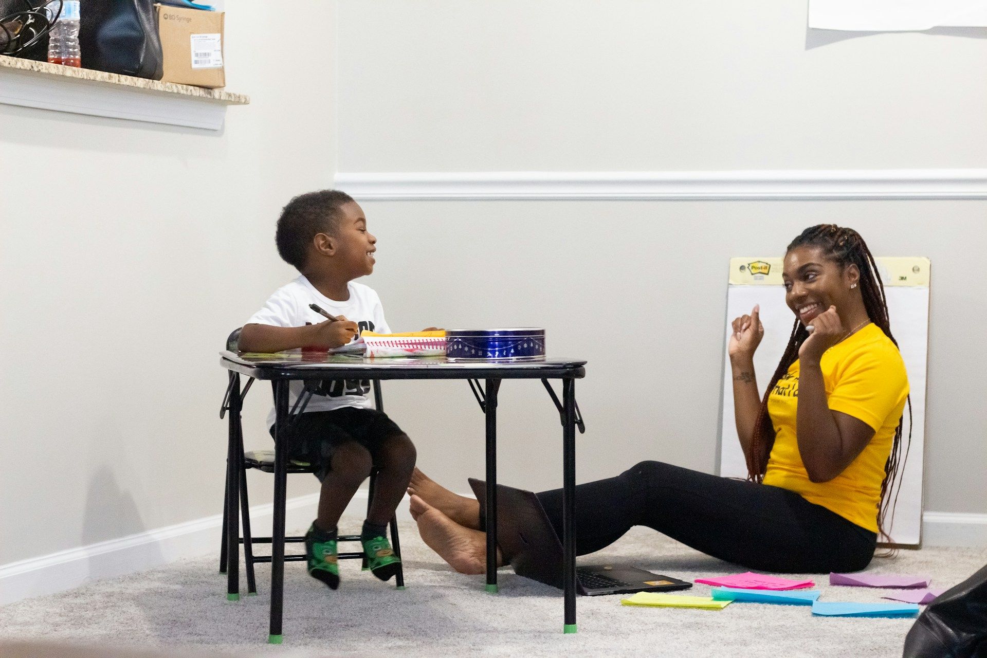 Une maman souriante en regardant son enfant étudier