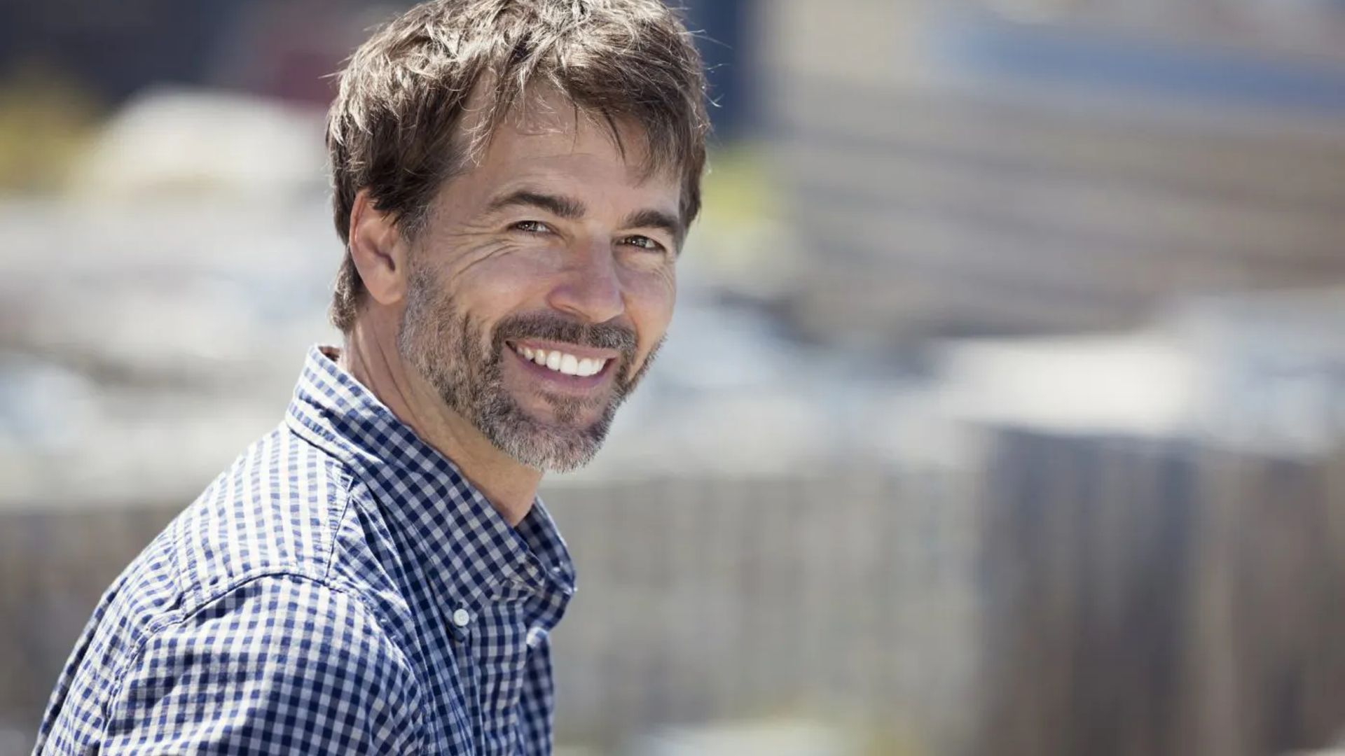 Image of a man in a blue checked shirt smiling