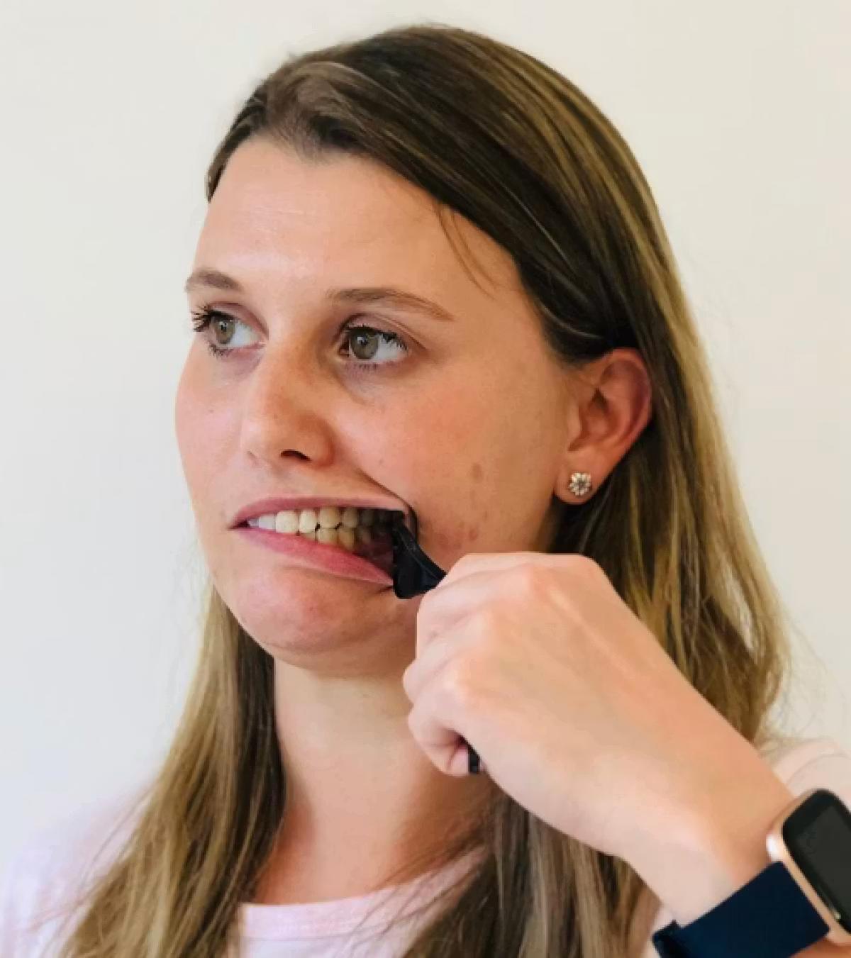 Image of a woman holding a spoon which is holding her left cheek