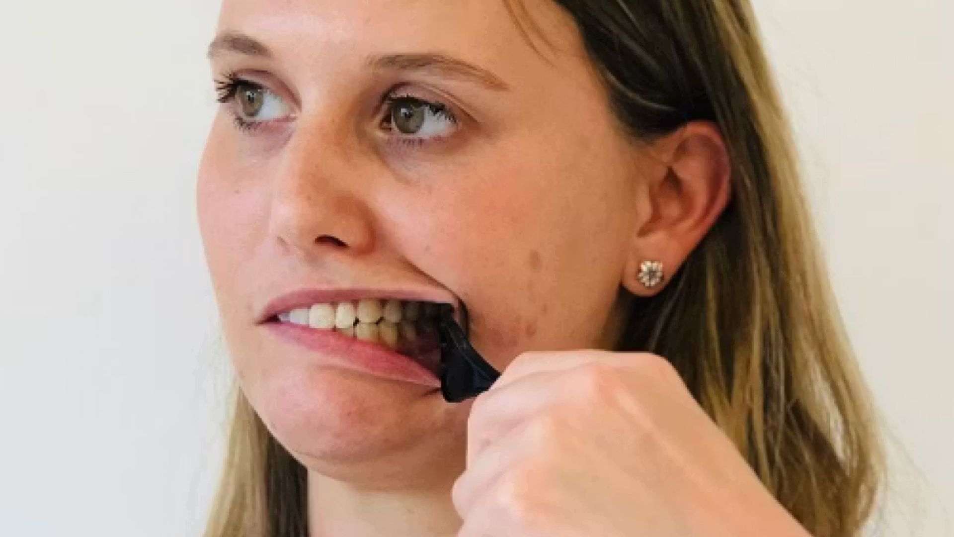 Image of a woman holding a spoon which is holding her left cheek