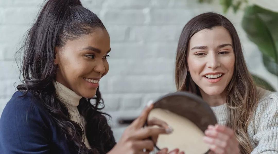 Image of two ladies looking at a mirror together and smiling