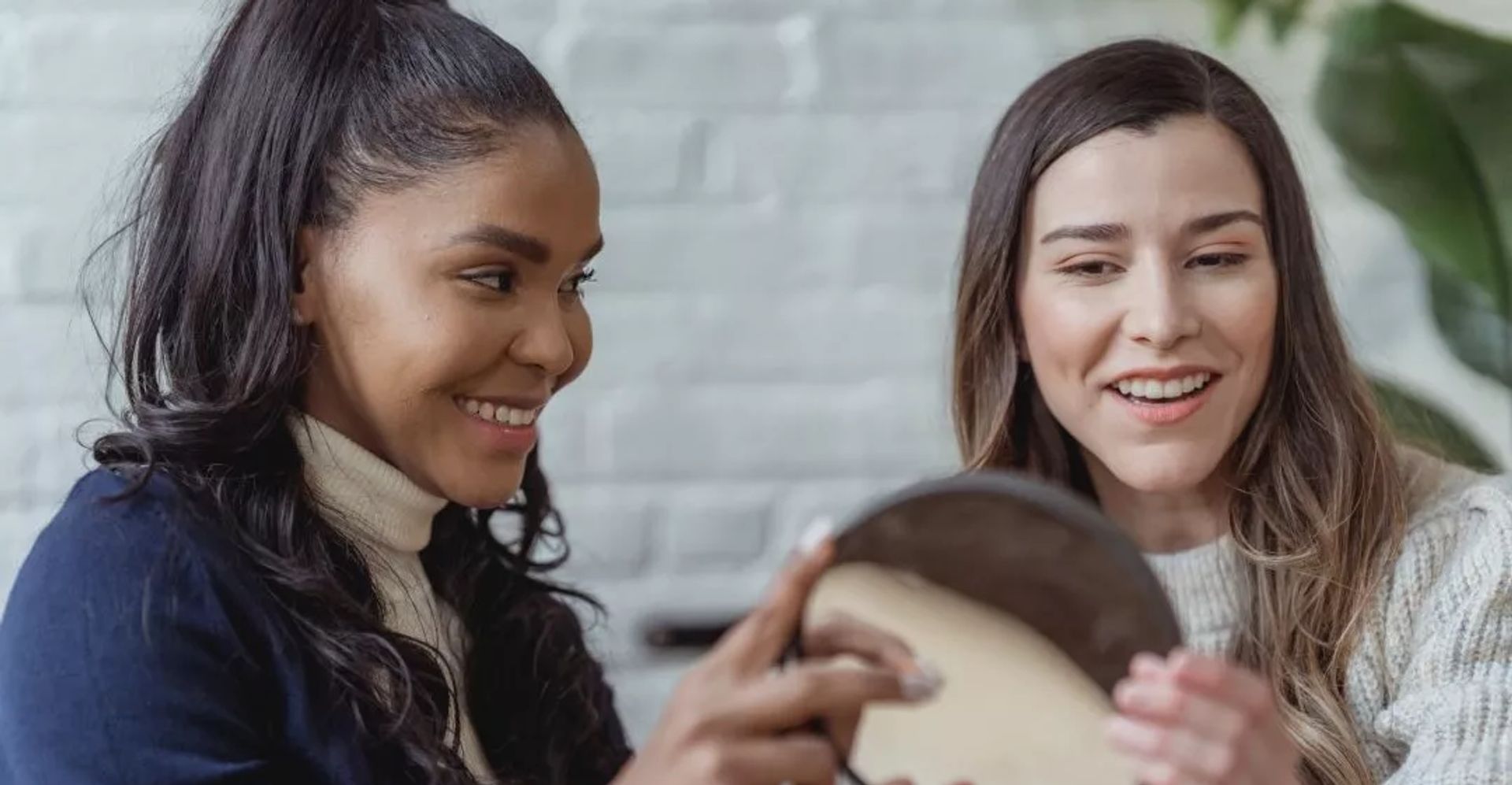 Image of two ladies looking at a mirror together and smiling