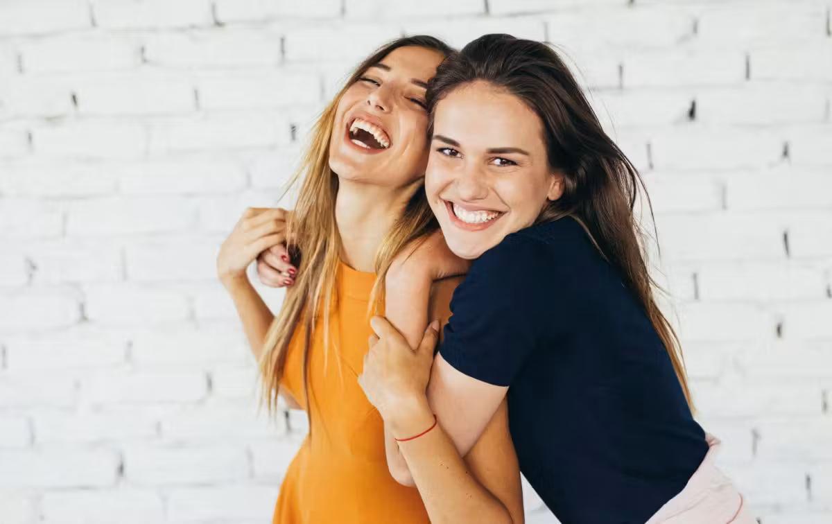 Teenage Girls Laughing Against Brick Wall I Stock 841836226 Ed