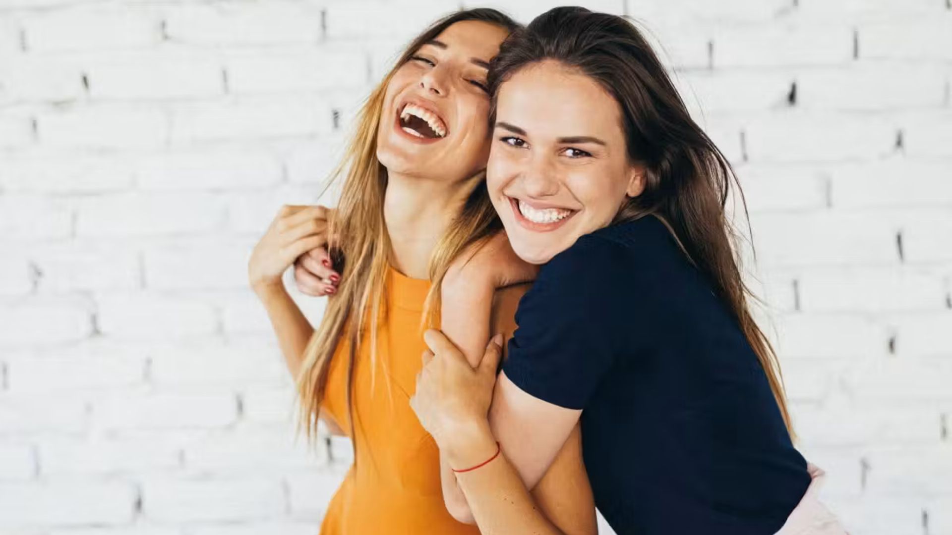 Teenage Girls Laughing Against Brick Wall I Stock 841836226 Ed