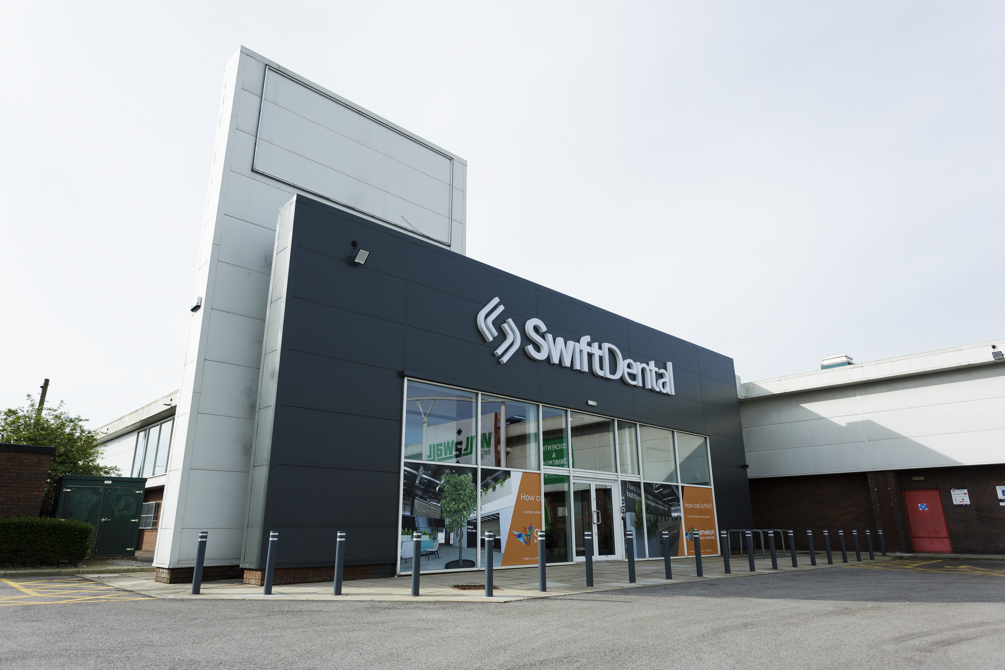Exterior view of a modern SwiftDental dental laboratory building featuring a dark facade with large windows and professional signage.