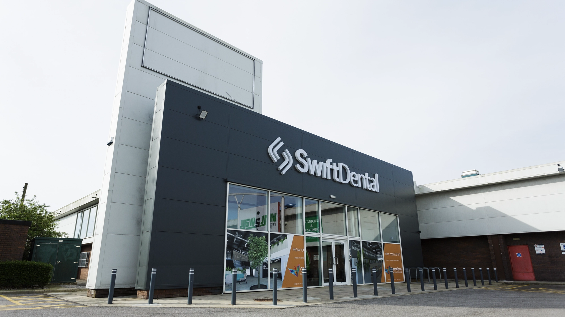 Exterior view of a modern SwiftDental dental laboratory building featuring a dark facade with large windows and professional signage.