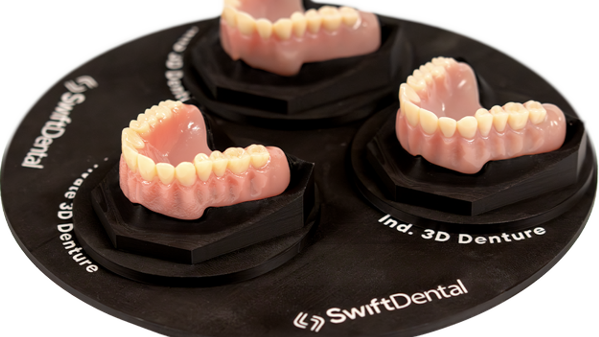Three complete denture prosthetics manufactured using 3D printing technology displayed on a black SwiftDental demonstration base, showcasing maxillary and mandibular denture options.