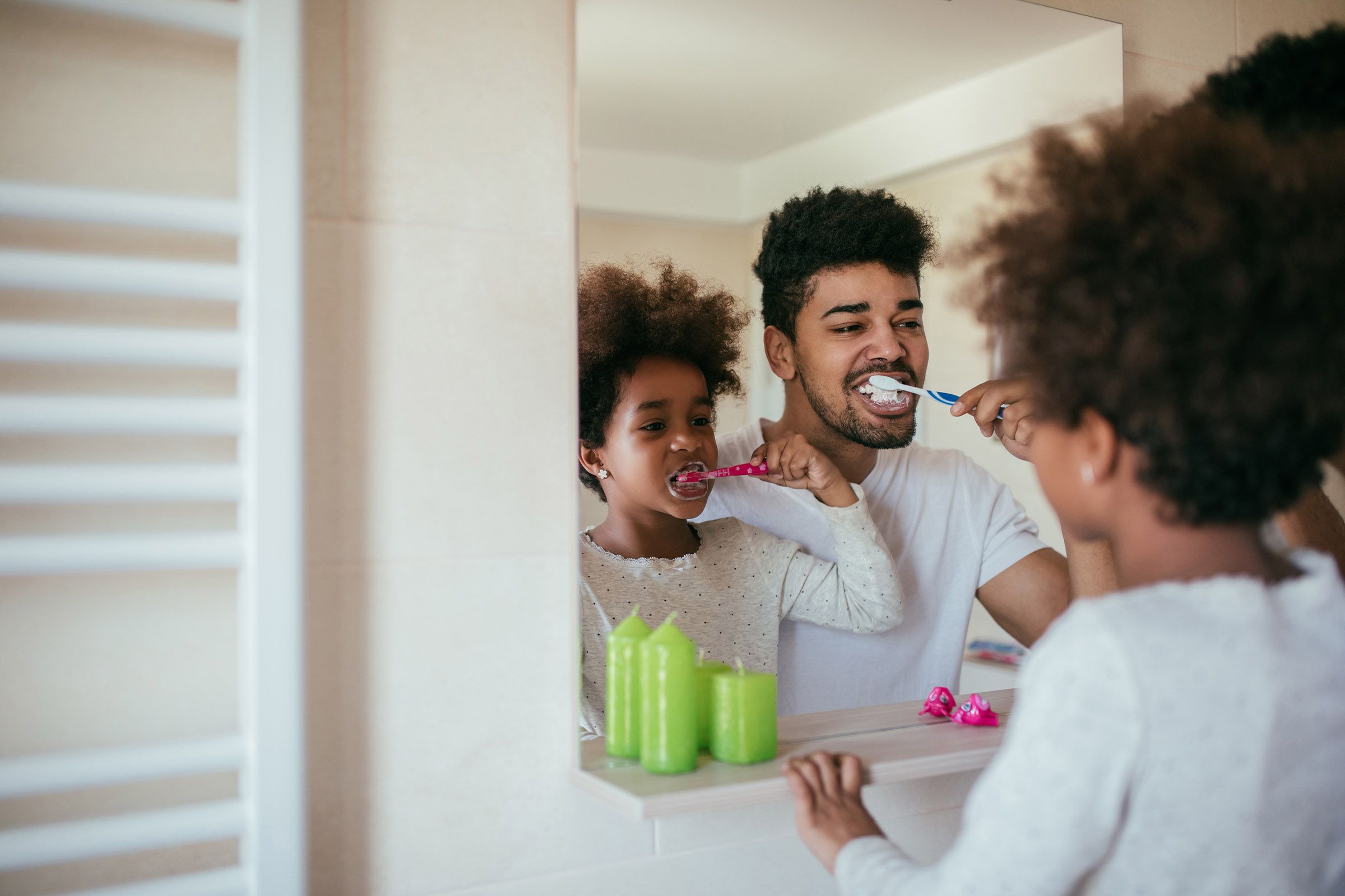 family brushing their teeth in mirror