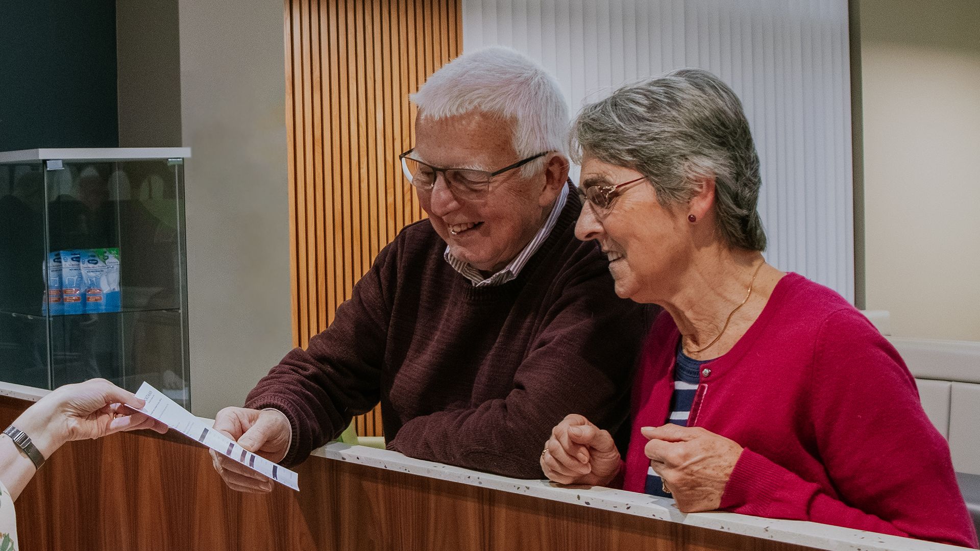 Senior mixed couple smiling at dental reception