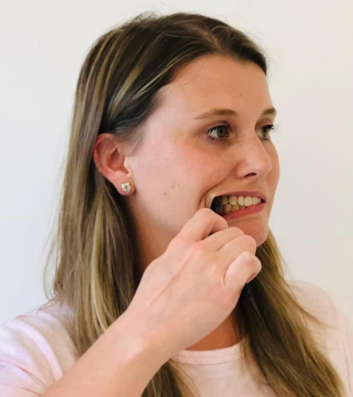Image of a woman holding a spoon which is holding her right cheek