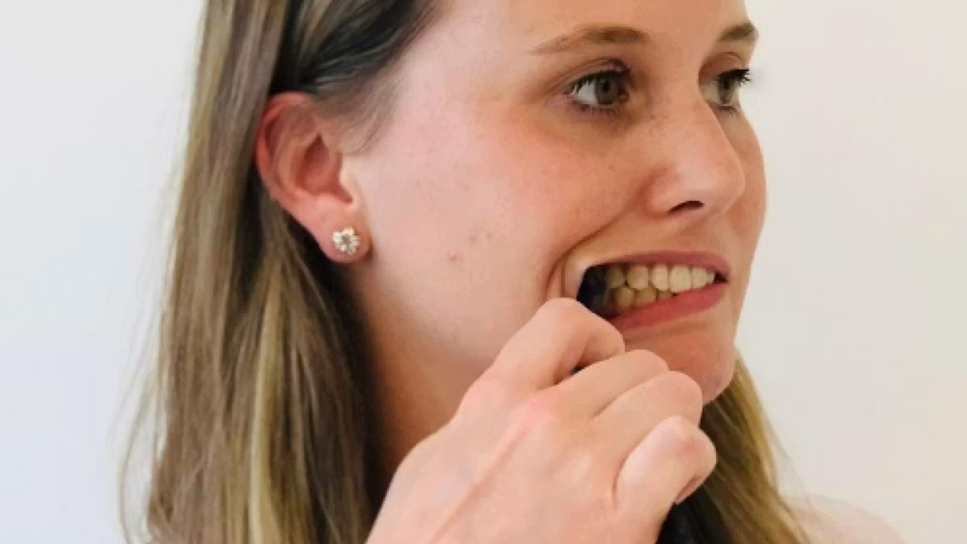 Image of a woman holding a spoon which is holding her right cheek