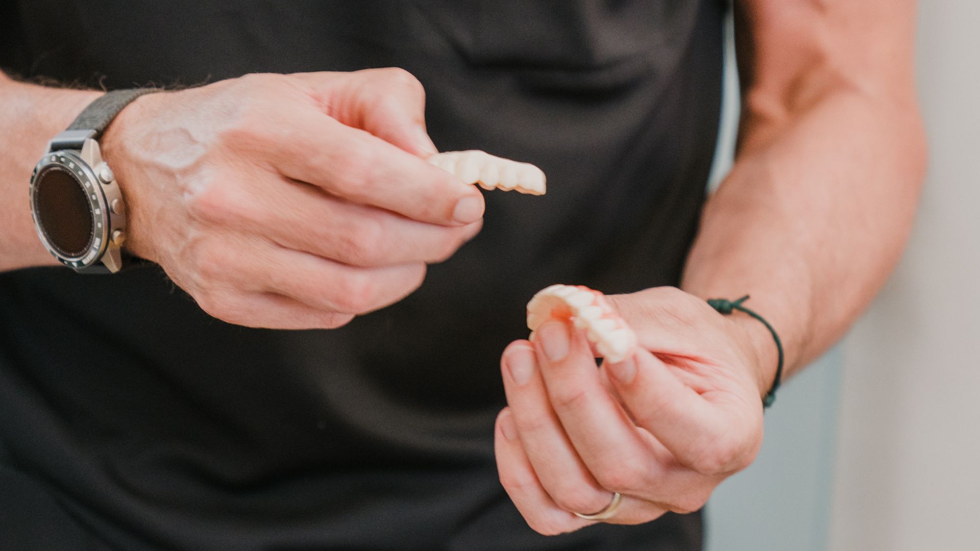 Two male dental professionals holding and demonstrating dental denture prosthetics