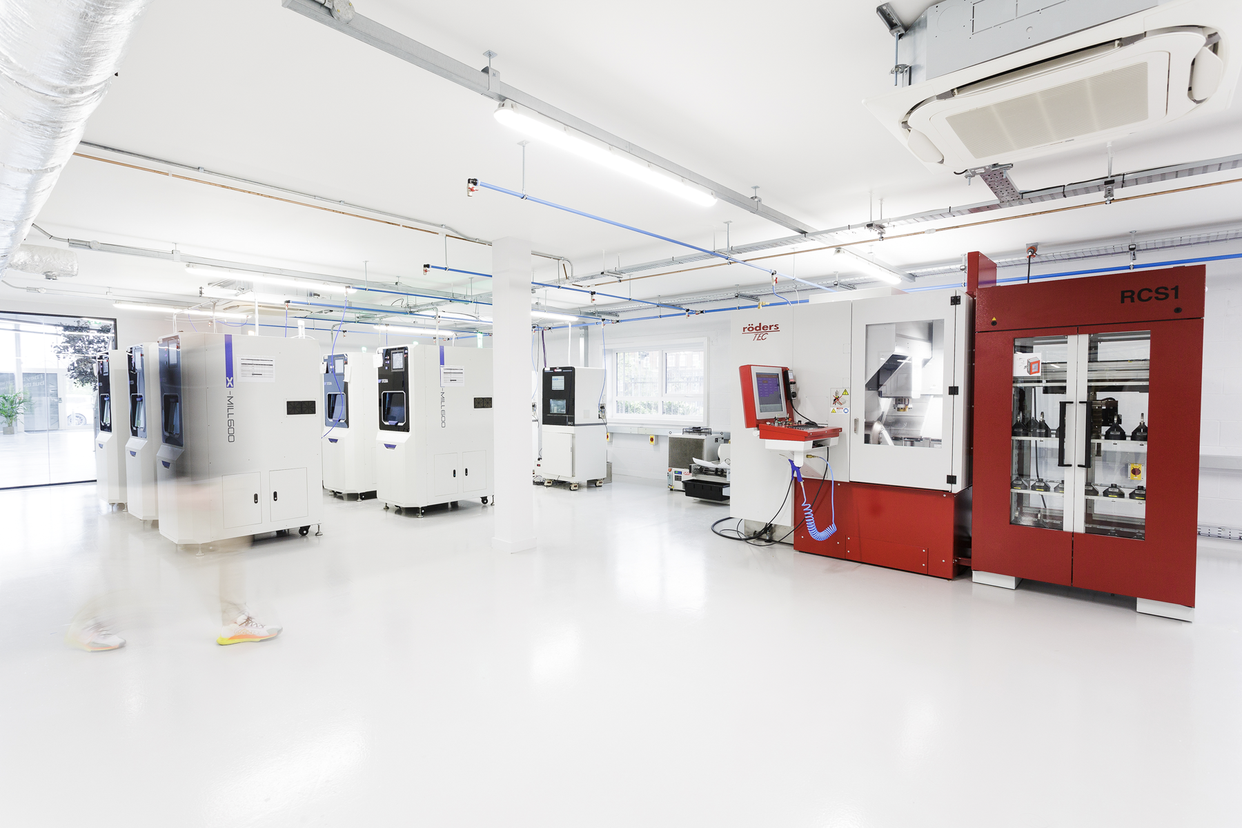 A bright, clean dental laboratory workspace showcasing multiple advanced CAD/CAM milling machines including an RCS1 unit and digital manufacturing equipment used for fabricating dental restorations.